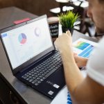 Profissional analisa gráficos e dados de negócios em um laptop.