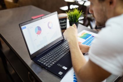 Profissional analisa gráficos e dados de negócios em um laptop.