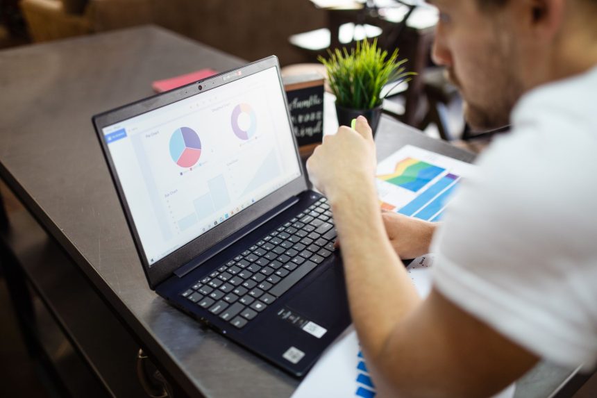 Profissional analisa gráficos e dados de negócios em um laptop.
