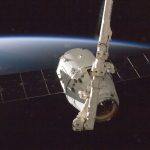 Satélite orbitando a Terra, com o planeta parcialmente iluminado ao fundo.