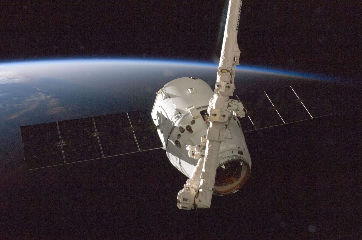 Satélite orbitando a Terra, com o planeta parcialmente iluminado ao fundo.
