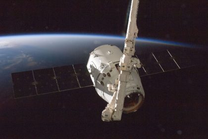 Satélite orbitando a Terra, com o planeta parcialmente iluminado ao fundo.