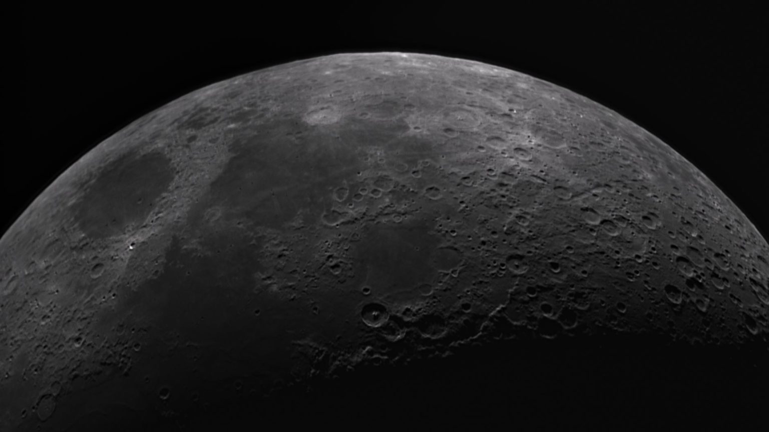 Superfície da Lua em preto e branco, com numerosas crateras e detalhes do relevo lunar