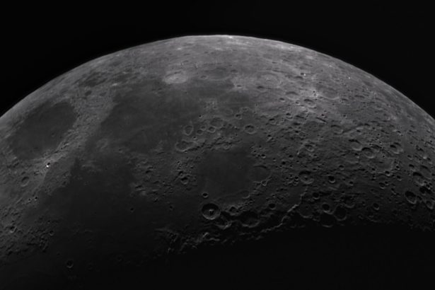Superfície da Lua em preto e branco, com numerosas crateras e detalhes do relevo lunar