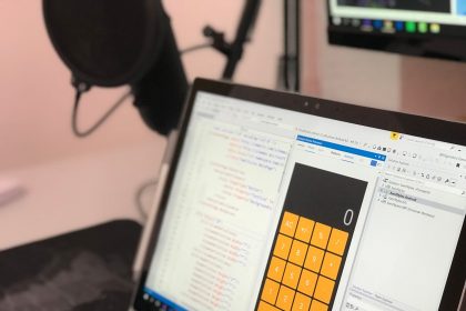 Laptop exibindo código e uma aplicação de calculadora em uma estação de trabalho moderna.