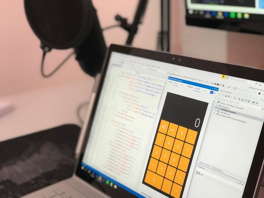 Laptop exibindo código e uma aplicação de calculadora em uma estação de trabalho moderna.