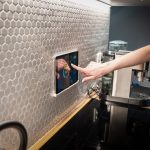 Painel touchscreen de controle de uma casa inteligente integrado à parede de uma cozinha moderna.