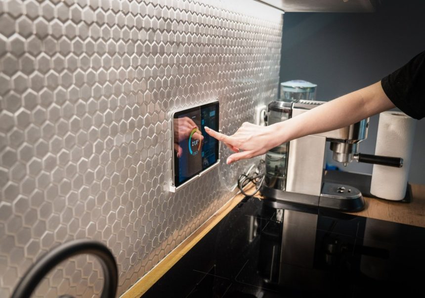 Painel touchscreen de controle de uma casa inteligente integrado à parede de uma cozinha moderna.