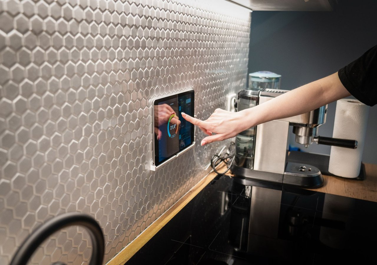 Painel touchscreen de controle de uma casa inteligente integrado à parede de uma cozinha moderna.