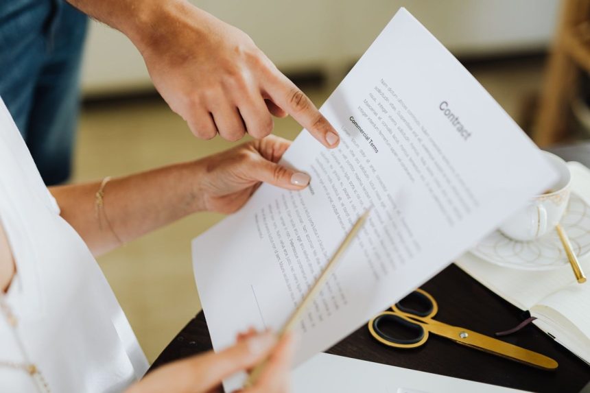Duas pessoas analisam e discutem um contrato sobre uma mesa de escritório.