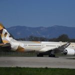 Avião da Etihad Airways taxiando em uma pista de aeroporto sob céu claro.