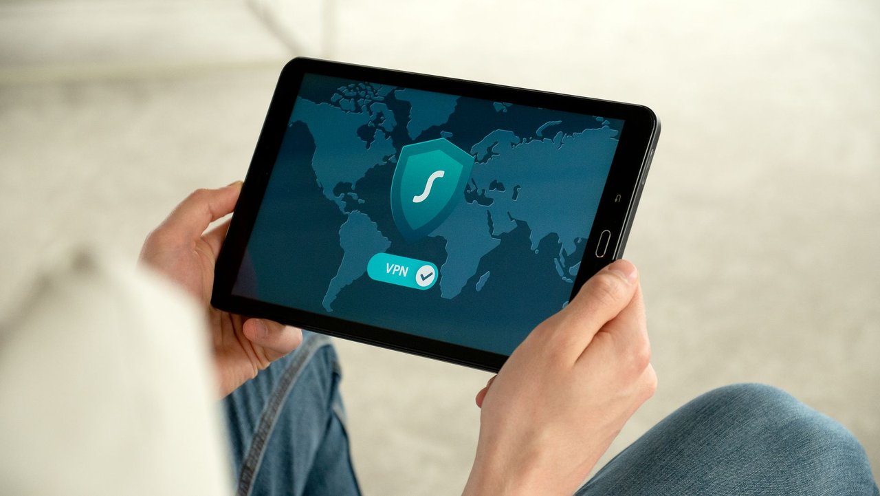 Pessoa segura um tablet que exibe uma tela de conexão VPN, associada à navegação segura na internet.