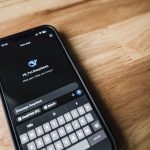 Smartphone exibindo uma interface de conversa sobre uma mesa de madeira